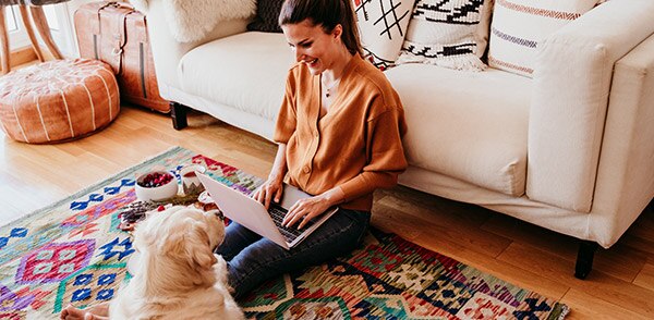 Woman sat on the floor with dog and laptop 