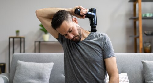 Man using an electric massager on his shoulder