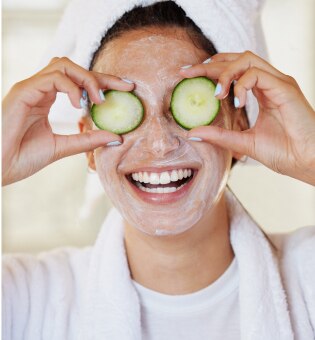 woman with facemask and cucumbers over eyes