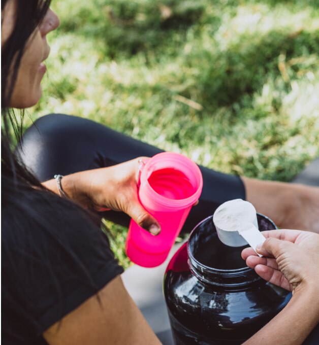 woman scooping protein powder into shaker