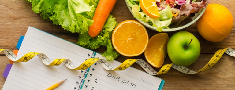 fruit and veggies with notebook and measuring tape
