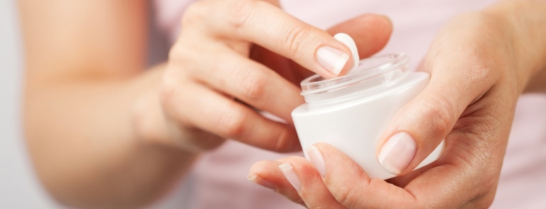 woman's finger next to pot of face cream moisturiser