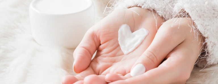 woman's hands with cream in the shape of a heart 