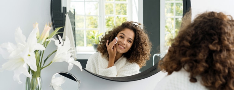 woman applying face  beauty product in mirror