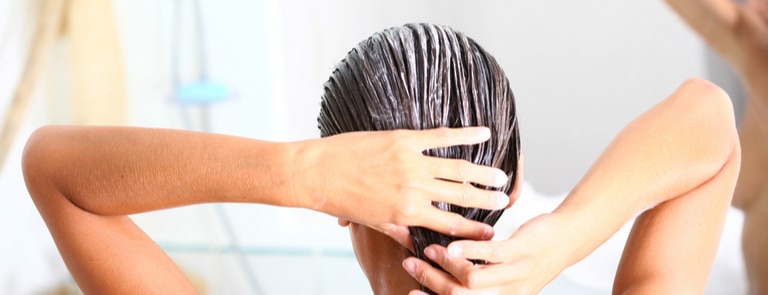 woman in bathroom applying hair mask to damp hair
