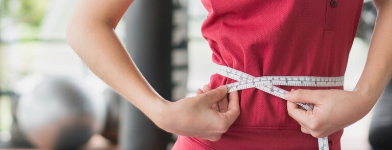 slim woman measuring waist