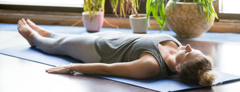 woman doing breathing exercise on yoga mat