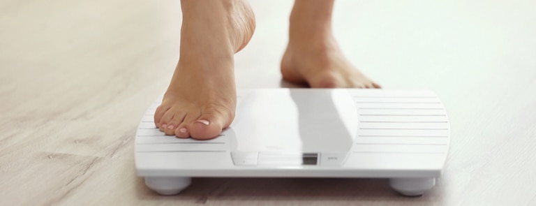 woman stepping onto weight scale