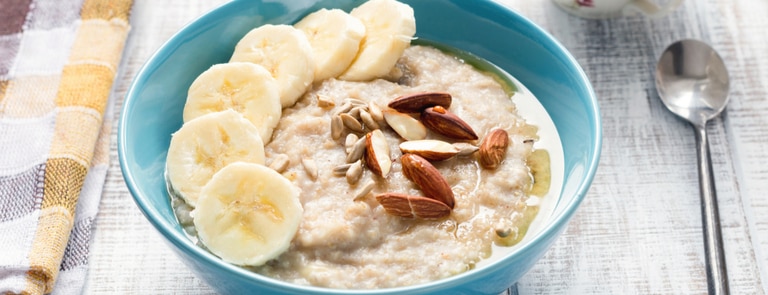 bowl of porridge with banana and almonds and honey