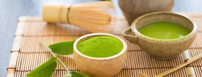 matcha green tea in teacup with powder on bamboo mat
