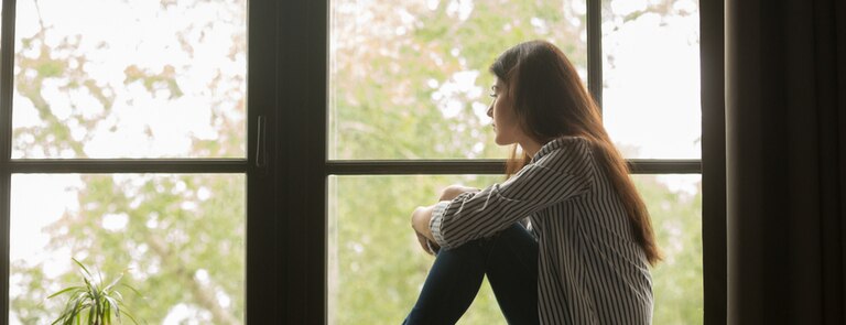 girl depressed sitting at window 
