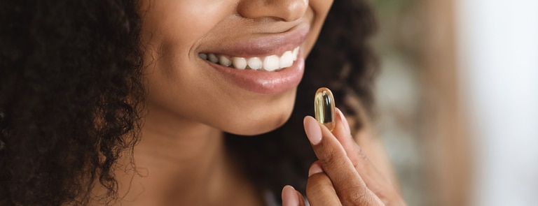 closeup of woman smiling taking omega 3 supplement