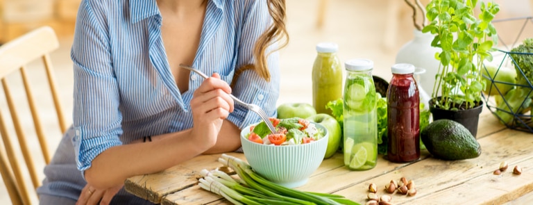 woman at table eating salad with fresh juice 
