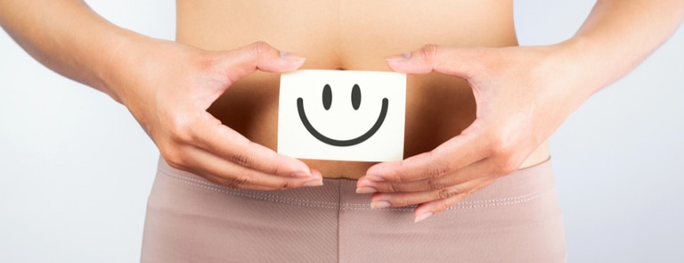 woman showing card of smiley face next to stomach