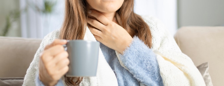 woman with sore throat and mug of tea