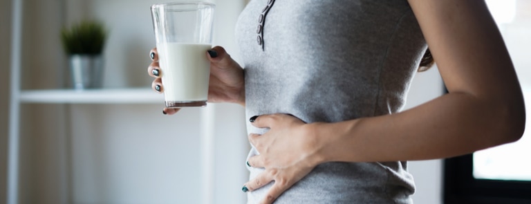 woman drinking glass of milk having stomach pain
