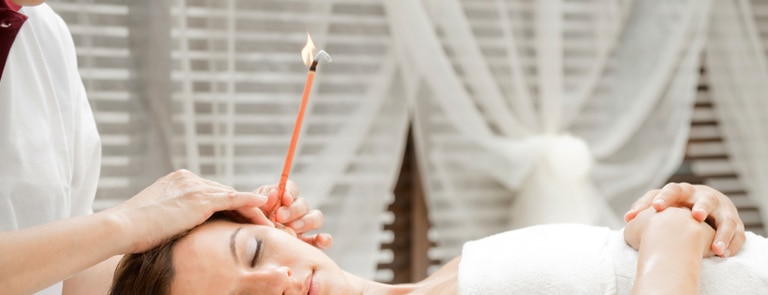 woman going through ear candling method at spa