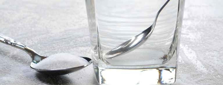 glass of water next to spoon of epsom salt for gargling