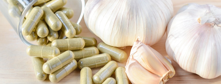 cloves of garlic next to garlic powder supplements