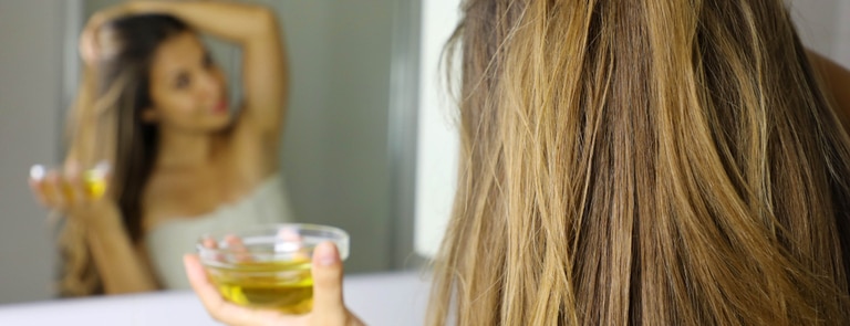 woman with dry hair applying argan oil hair mask