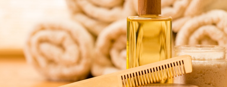 bottle of argan hair oil next to wooden comb