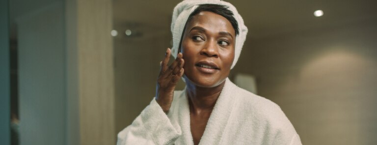 mature woman applying natural beauty product to face