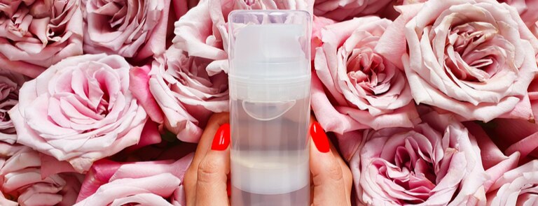 closeup of natural lubricant in bottle with fresh rose flowers