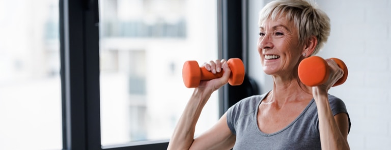 mature menopausal woman holding weights for strength training
