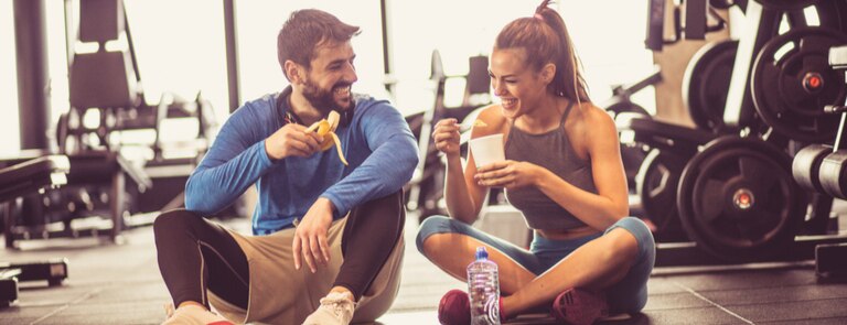 two people sat in the gym drinking pre-workout 