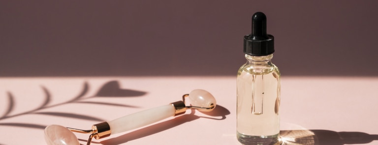face serum with a quartz roller on a pink background 