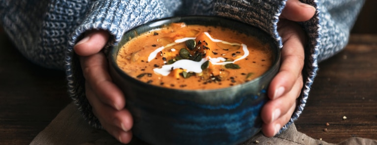 women holding a warm bowl of vegan soup 