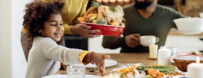 african american family eating turkey for thanksgiving at dinner table