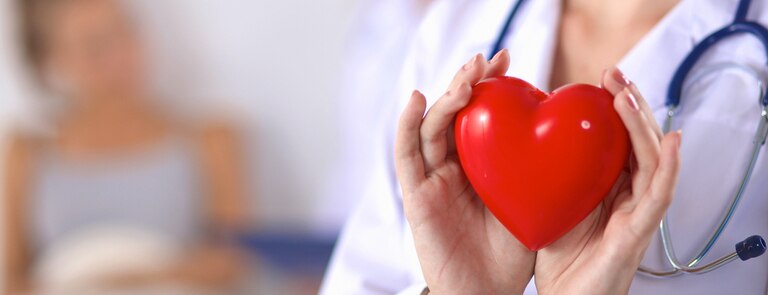 doctor holding heart shape to patient to demonstrate heart disease awareness