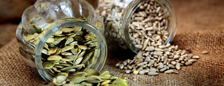jar of sunflower seeds next to jar of pumpkin seeds