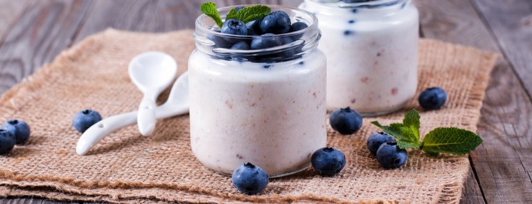 glass jar of yoghurt topped with blueberries