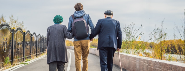 man helping two elderly people to walk 