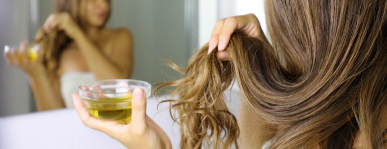 woman applying hair oil to hair