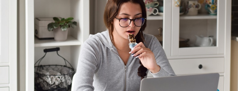 woman eating meal replacement bar while working from home