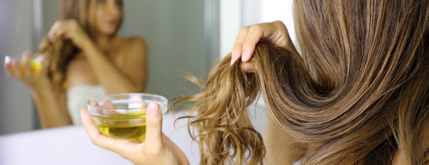 woman applying castor oil to hair for split ends and dry brittle hair 