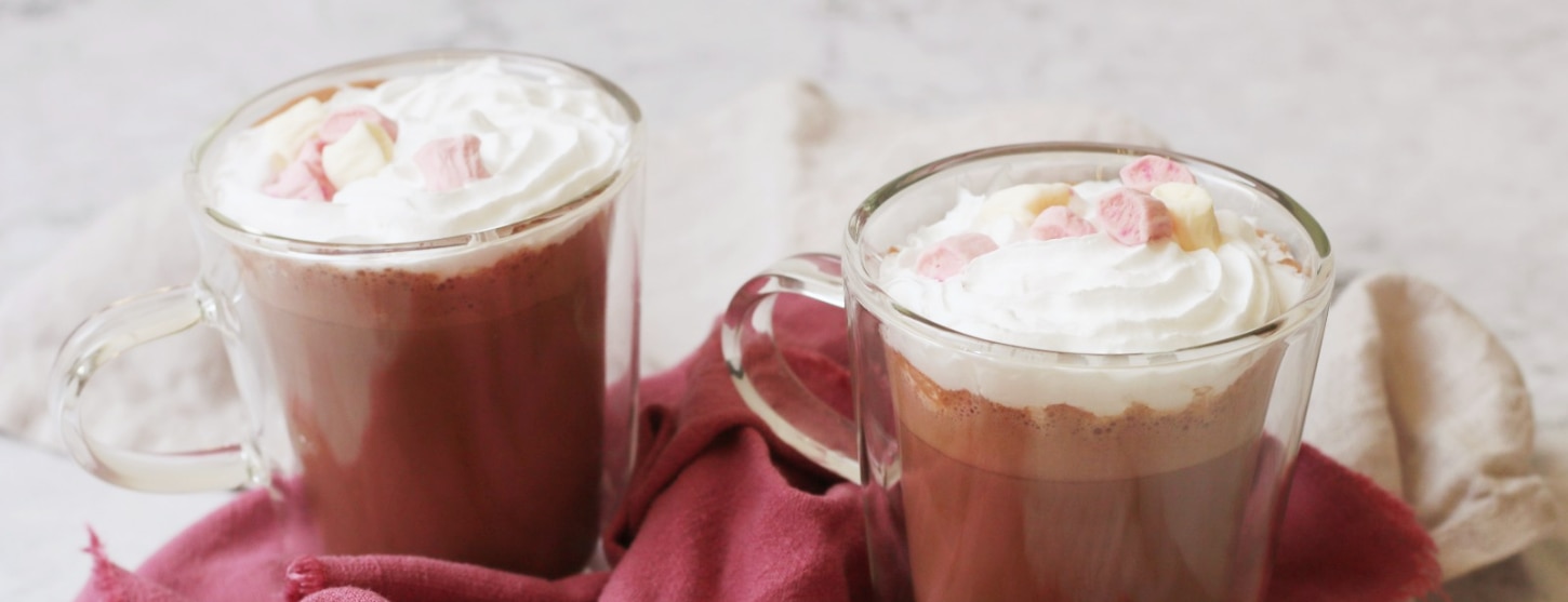 cacao powder hot chocolate in two cups topped with vegan marshmallows