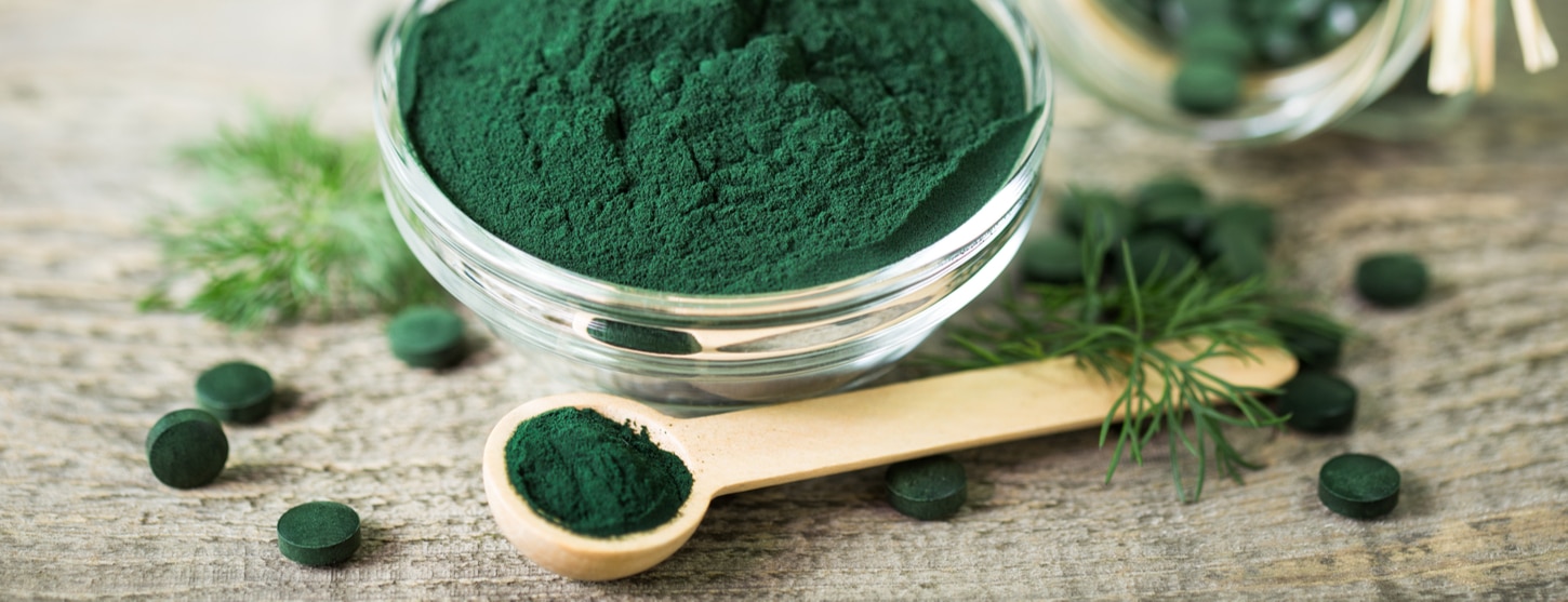 spirulina powder in bowl with tablets on the side