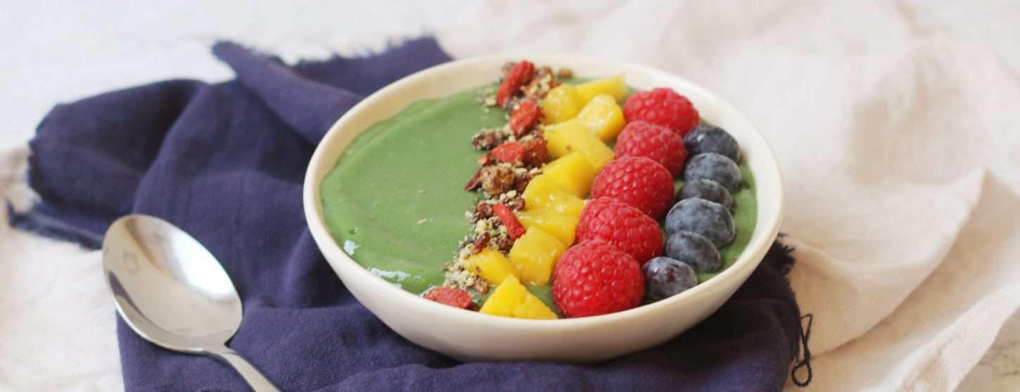 spirulina smoothie bowl topped with fresh mango, raspberries and strawberries 