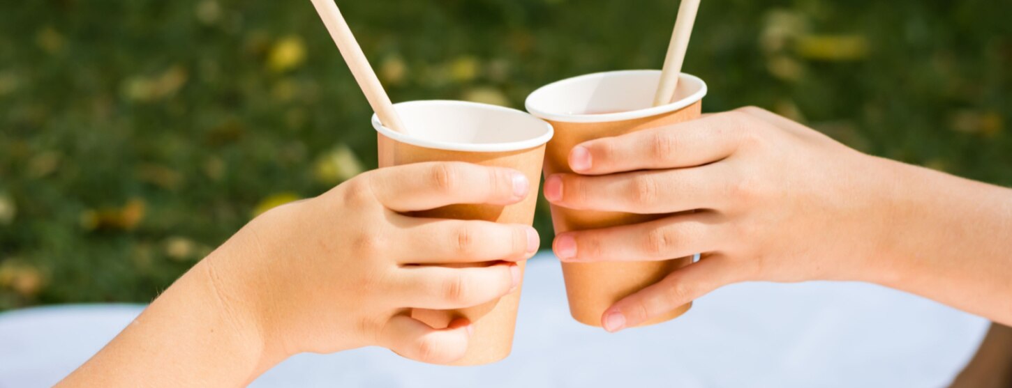 two people holding eco friendly paper cups at a picnic for sustainability