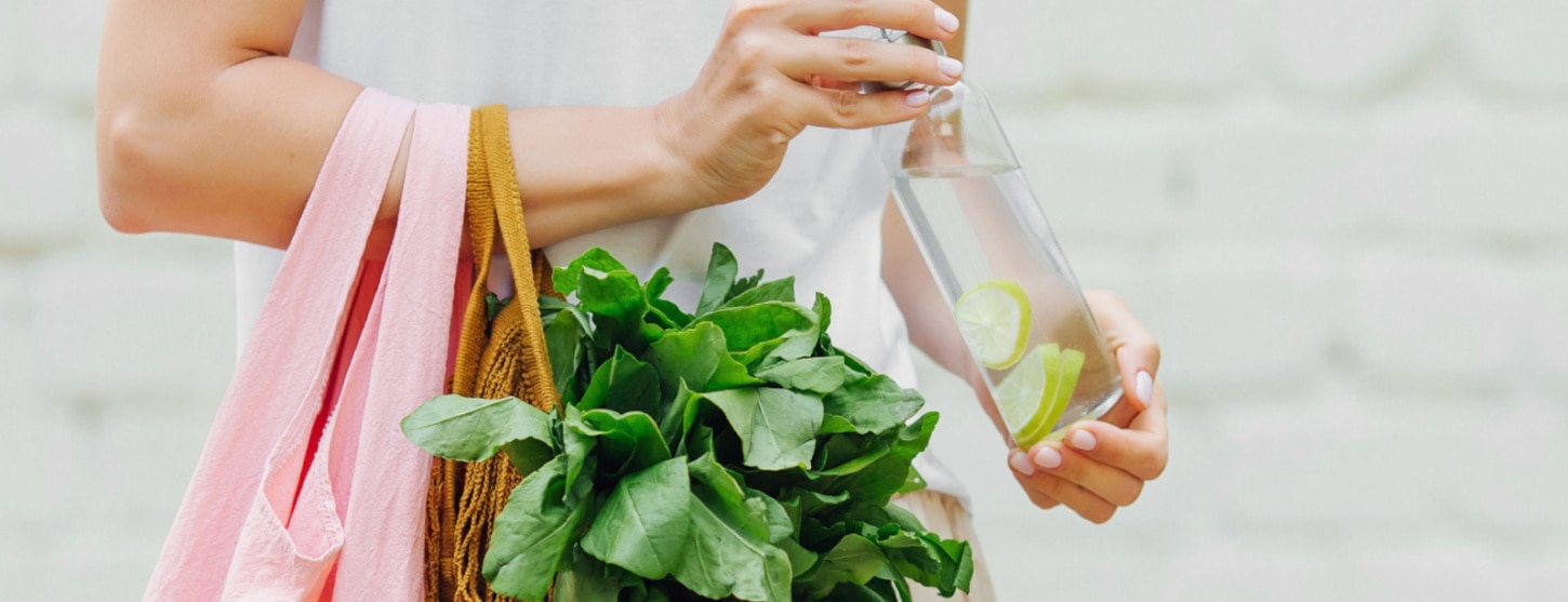 woman holding cloth bag with plants and reusable water bottle for zero waste awareness 