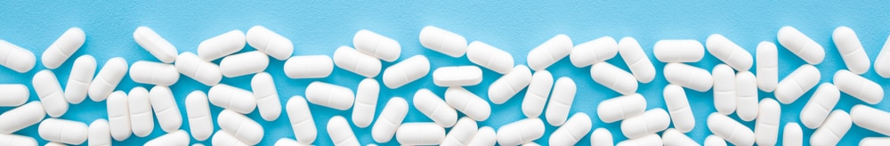 white capsule tablets laying on blue background