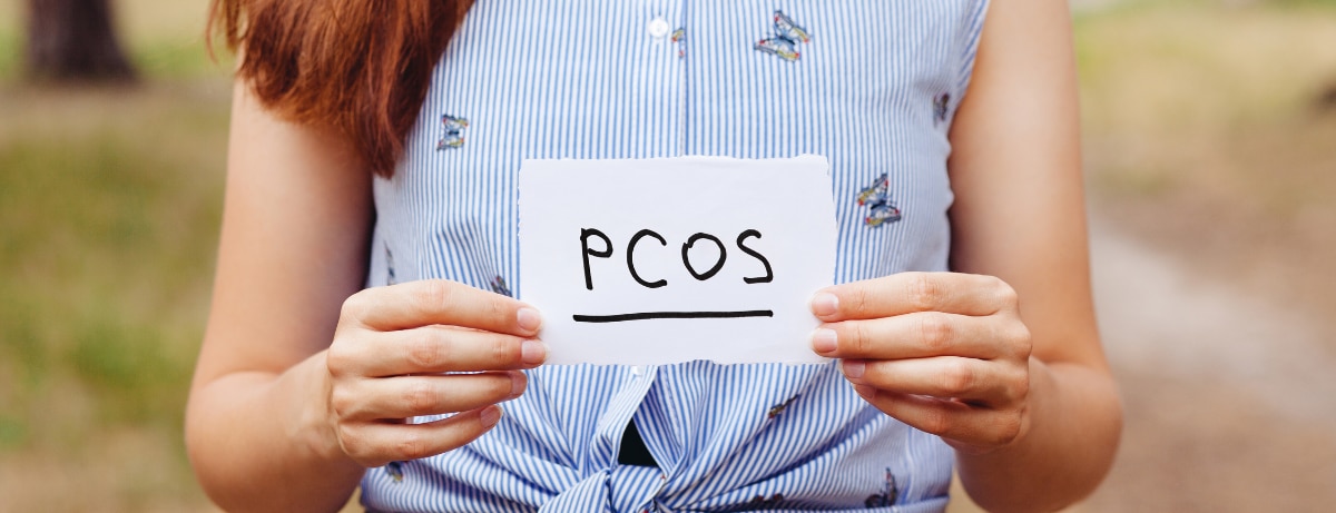 woman holding piece of paper with PCOS