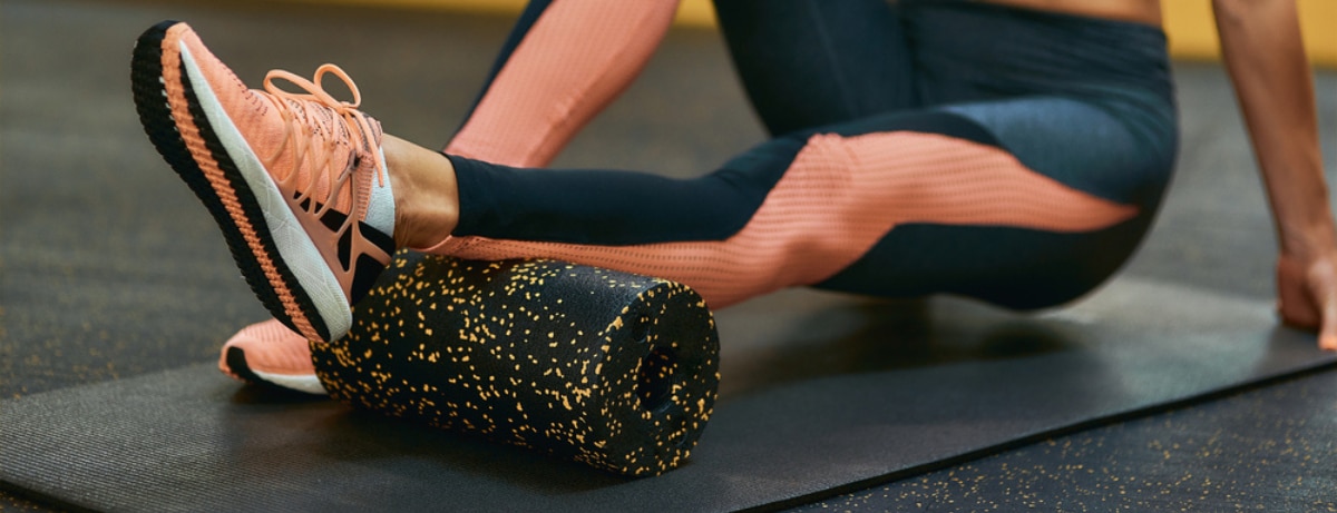 lady using a foam roller on an exercise matt