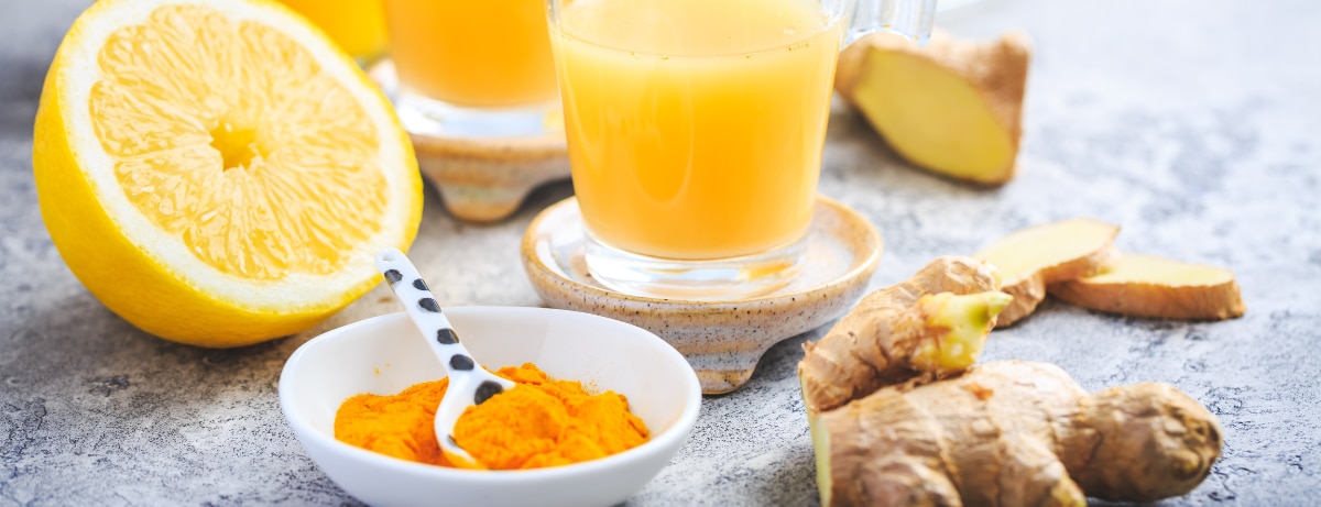 selection of orange juice, ginger stem and oranges on a slate background