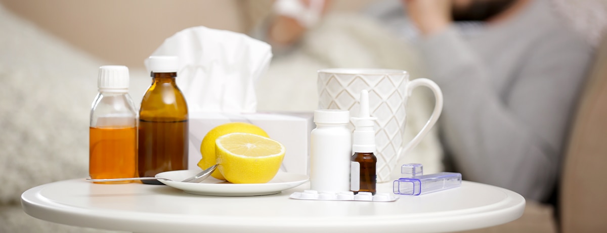 oranges, mug and flu medicine on a bedside table