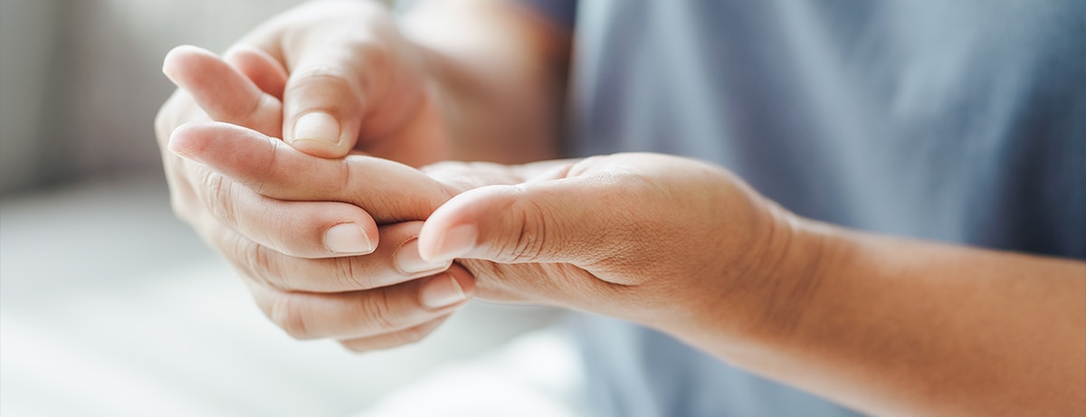 types of arthritis - a man rubbing his hand as it is in pain caused by a type of arthritis